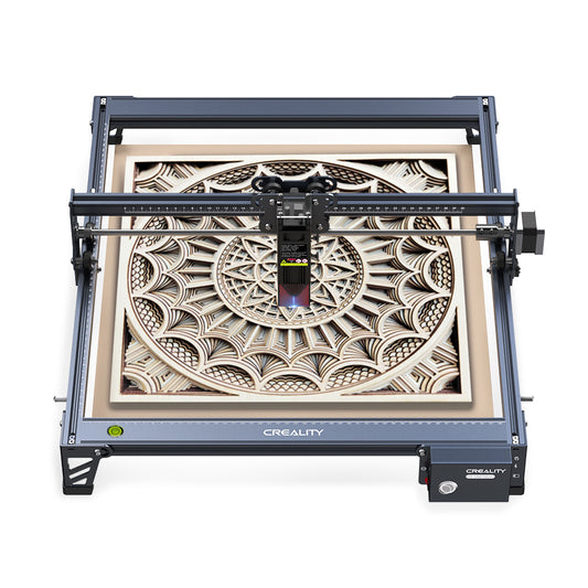 An overhead view of a Falcon 5W Laser Engraver cutting an intricate, symmetrical design into a wooden surface. The design features a complex pattern of concentric circles and geometric shapes. The machine is blue and proudly displays the CrealityFalcon logo on the front. 1000