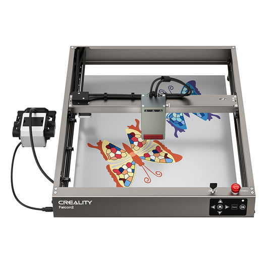 Top view of a CrealityFalcon Falcon2 40W Laser Engraver and Cutter. The machine is crafting two colorful mosaic butterfly designs on a metal sheet. The surrounding frame and mechanical components are visible, with a control box on the left connected by cables. 1000