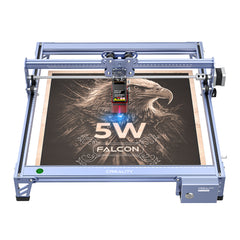 A blue CR-Laser Falcon 5W Laser Engraver from CrealityFalcon, featuring a wood panel with an intricately laser-etched eagle design and the text "5W FALCON" below it. The ultra-fine engraving precision of this device, versatile with over 300 materials, makes it a standout in its category.