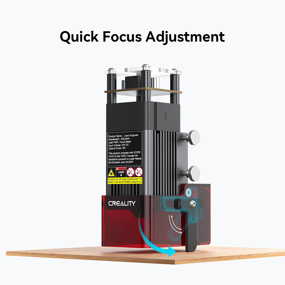 Image of a CrealityFalcon CR-Laser Falcon 5W Laser Engraver with the text caption "Quick Focus Adjustment" above it. The laser head is mounted on a wooden platform. An arrow graphic points to a knob, highlighting the focus adjustment mechanism on this ultra-fine engraving precision machine. Safety warnings and technical specifications are visible on the laser head.