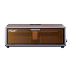 The Falcon A1 10W Enclosed Laser Engraver and Cutter by Creality features a compact, rectangular shape with CoreXY technology. It has a sleek black and gray metallic exterior, topped off with a transparent orange-tinted cover revealing the interior mechanism.