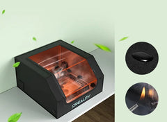 A 3D printer with an orange-tinted transparent lid and "CREALITY" branding sits calmly on a table, resembling the quietness of the Creality Falcon Air Purifier Bundle. Green leaves surround the scene, while close-ups showcase a button and light-emitting nozzle for 10W engraving machines.