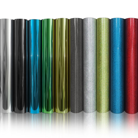 A row of nine upright rolls of metallic and glittery vinyl, including silver, black, blue, green, gold, gray, silver sparkle, green sparkle, and red sparkle. They stand side by side on a reflective surface ready for customization with a CrealityFalcon 10pcs HTV Heat Transfer Vinyl Paper for Falcon Laser Engraving.
