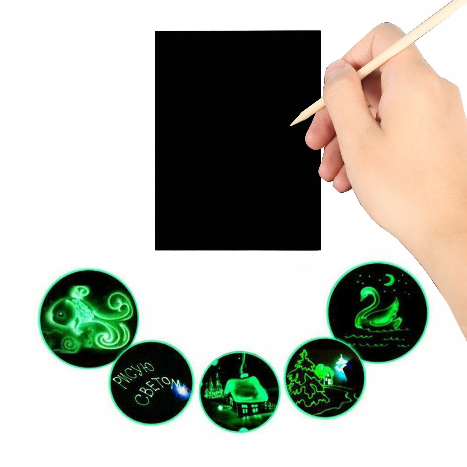 A hand holding a wooden stylus hovers over a black scratch sheet. Below, glowing green designs reveal an octopus, the words "Рисую светом" (drawing with light), a nighttime scene with a house, a swan on water, and a Christmas tree near a house. The precision resembles that of an engraver's touch achieved with the 50pcs A4 Luminous Scratch Paper Fluorescent Scratch for Falcon Laser Engraving by CrealityFalcon.